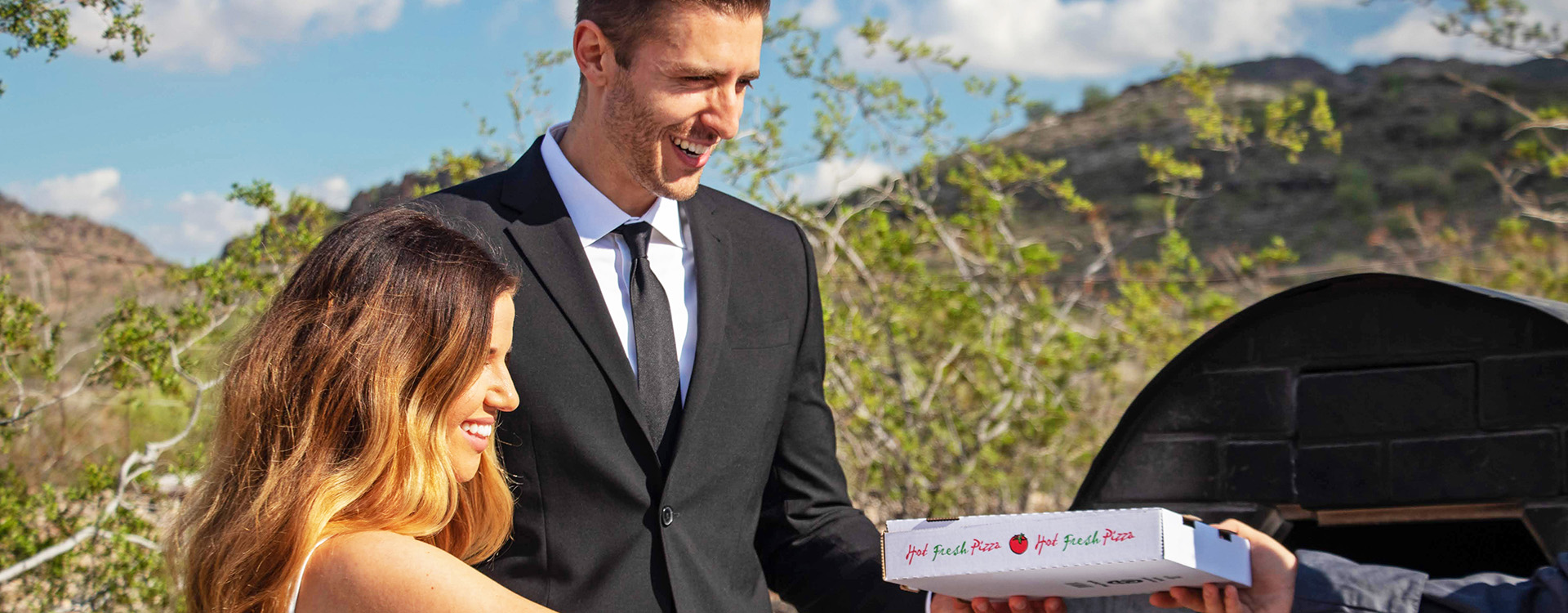 A man holding a pizza box next to his bride